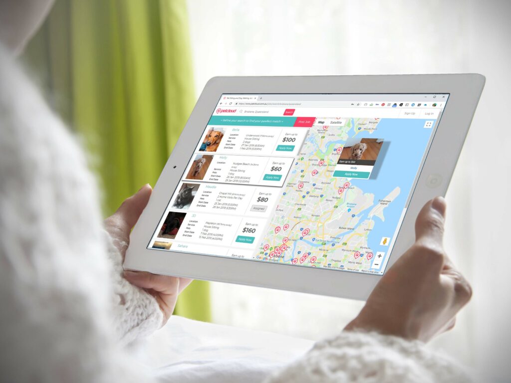 A person holds a tablet displaying a pet adoption website. The screen shows a list of available pets with photos, descriptions, and adoption fees on the left side. A map on the right is marked with pins indicating locations of available pets, along with dog walking guidelines for prospective owners.